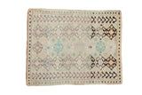 Distressed vintage Oushak rug featuring geometric floral motifs in soft tones of ivory, turquoise, and charcoal.