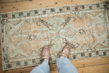 Overhead view of a distressed Oushak runner, showing muted beige, seafoam green, and terracotta tones.