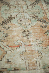 Distressed Oushak runner with muted beige and seafoam green, displaying exposed foundation.