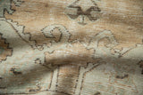 Worn pile texture of a distressed Oushak rug in soft beige, jade green, and terracotta.