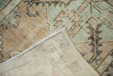 Distressed vintage Oushak rug corner revealing worn pile, muted beige, and hand-knotted reverse.