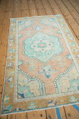 Distressed Oushak rug corner showing shaded deep gold border and germinating plants.