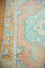 Distressed Oushak rug detail: dusty sandalwood field, mint green motifs, and shaded gold border.