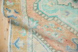 Distressed vintage Oushak rug's worn texture, with faded gold border and soft mint tones.