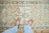 Mint green and dusty gold floral pomegranate motifs on a distressed vintage Oushak runner.