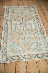 Distressed Oushak runner corner detail: geometric floral border in soft mint green and dusty gold tones.