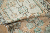 Distressed Oushak runner's texture detail, showcasing mint green, dusty gold floral motifs and visible wear.