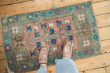 Distressed Oushak rug pile revealing faded dusty blush, slate blue, and aqua green tones.