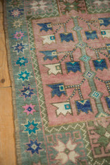 Distressed Oushak rug edge detail: worn pile, dusty blush field, sage green starburst floral border.
