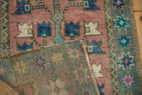 Folded vintage distressed Oushak rug corner showing woven back and dusty blush serrated blossoms.