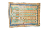 Vintage distressed Oushak rug with a geometric pattern of diamond medallions in sand, mint green, and blue.