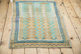 Angled perspective of a distressed Oushak rug showing its full geometric pattern and hand-knotted character.