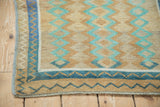 Close-up of a distressed Oushak's worn knots and geometric blue and sand zig-zag border.