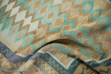 Textured weave of a vintage Oushak rug folded to show sand, mint, and blue geometric patterns.
