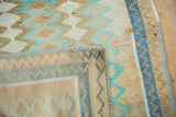 Folded corner of a distressed Oushak rug showing the hand-knotted back and side cord selvage.
