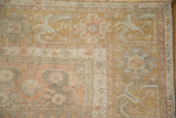 Corner detail of a vintage Oushak rug with softly worn, dusty gold arabesque borders.