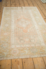 Distressed vintage Oushak rug seen from a low angle, emphasizing its time-softened medallion and border.