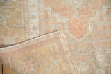 Folded corner reveals the tight hand-knotted back of a distressed Oushak rug.