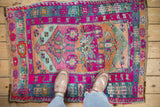 Close-up detail of Vintage Kars rug. Heavy abrashes, geometric motifs in magenta, seafoam, and gold.