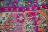 Geometric ram's horn and floral motifs in magenta, dusty blue, and glittering gold on Kars rug.