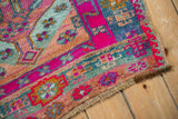 Vintage Kars rug corner showcasing geometric motifs in magenta, seafoam, and glittery golden tones.