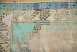 Checkered dusty blue border alongside a pale turquoise stepped prayer design on a vintage rug.