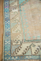 Angled view of the checkered border and low, even pile on a vintage Oushak rug.
