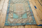 Overhead angle of a distressed Oushak rug with a turquoise stepped prayer design.
