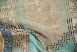 Worn, low pile and stepped geometric border in turquoise on a vintage distressed Oushak rug.