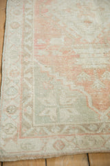 Distressed Oushak rug corner detail, highlighting soft blush, ivory, and seafoam green border.