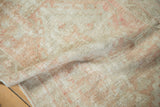 Faded dusty blush and ivory patterns on the distressed Oushak rug runner's pile.