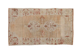 Distressed vintage Oushak rug featuring a double medallion on a heavily abrashed field of sand and gold.