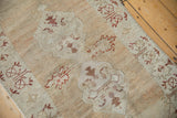 Angled detail of a distressed Oushak rug showing time-softened wear and palmette design.
