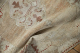 Draped fold of a vintage Oushak rug showing its soft, sand-colored texture and even wear.