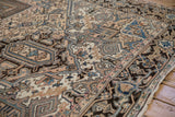 Distressed vintage Mehrivan carpet with serrated geometric patterns in beige, blue, and brown tones.