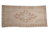 Distressed vintage Oushak runner with central medallion, floral design, and germinating border in muted ivory, copper, blue, 4' x 8'.