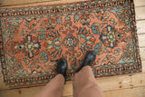 Vintage Lilihan rug's traditional floral pattern in dusty blush, ocean blue, and navy, with boots.