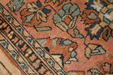 Dusty blush Lilihan rug field with floral palmettes, showing pile wear and edge tatter.