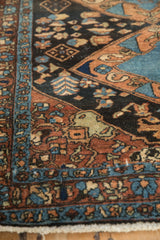 Finely woven floral border and pinwheel blossoms on a dark brown vintage Persian Heriz rug.