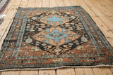 Angled view of a vintage Heriz rug showing the blue double medallion and characterfully tattered sides.