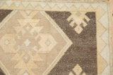 Distressed pile of an Oushak rug, with geometric gul patterns in ivory and brown.