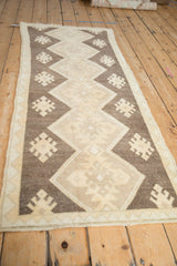 Distressed Oushak runner with geometric gul medallions and zigzag overlays in chocolate, ivory, and beige.