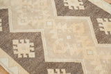 Distressed Oushak rug close-up: ivory, beige, and brown geometric gul medallions with zigzag fields.