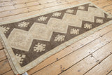 Ivory fringe and distressed geometric patterns with even wear on this Oushak rug end.