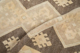Distressed Oushak rug runner's soft geometric pattern detail in beige and chocolate brown.