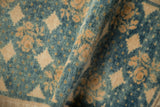 Folded distressed Oushak rug pile, revealing sapphire blue and jade green hues with ivory floral motifs.