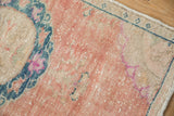 Distressed vintage Oushak rug corner: time-softened cantaloupe, dusty teal, magenta, with mostly even wear.