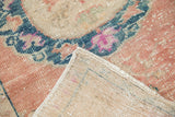 Distressed Oushak rug pile in cantaloupe and dusty teal, displaying its woven reverse.