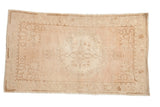 Distressed vintage Oushak rug with a faded floral medallion and spandrels in dusty rose, sand, and ivory.