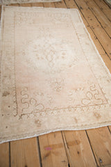 Angled view of a distressed Oushak rug's corner, showing the worn pile and intact selvage.